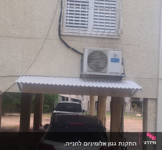 גגון אלומיניום מעל חניה עם מזגן מותקן על הקיר